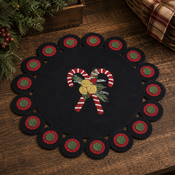 Black Christmas candle mat with crossed candy canes, greenery, berries, and bells on a decorative scalloped border.