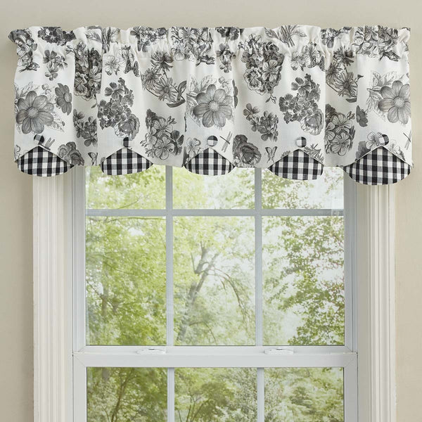 Black and white floral farmhouse valance with gingham scalloped edging hanging above a bright cottage style window.