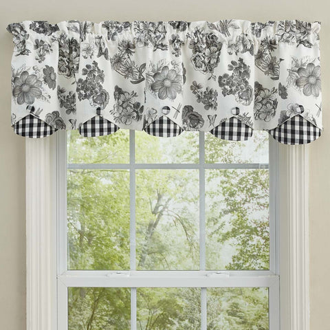 Black and white floral farmhouse valance with gingham scalloped edging hanging above a bright cottage style window.