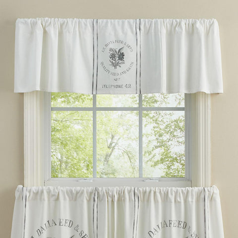 White farmhouse seed sack valance with vintage grain sack style print hanging above a bright country kitchen window.