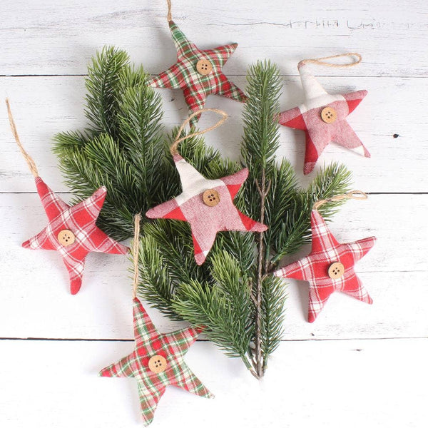 Primitive plaid fabric star Christmas ornaments with wooden button accents displayed on evergreen branches.