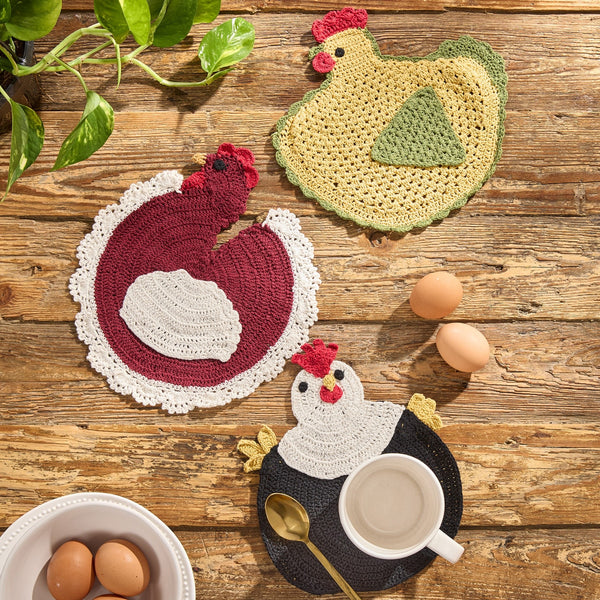 Henrietta crochet chicken trivets in primitive farmhouse colors including barn red, black, mustard, and cream displayed as a set of three kitchen trivets.