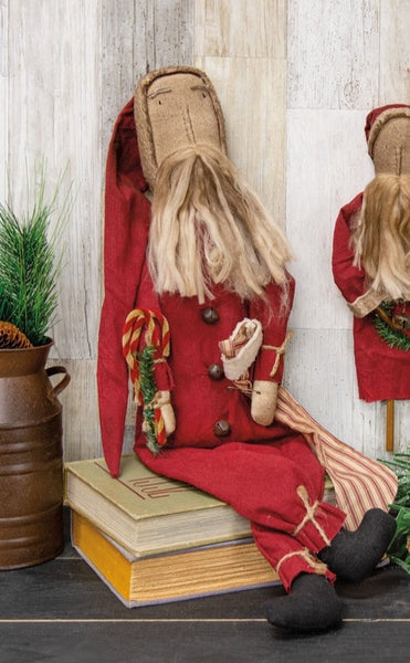 Father Christmas Doll With Candy Canes & Stocking is a primitive Santa doll with a classic red suit and distressed fabric finish. Doll is stuffed and features a striped stocking accent on one arm and a spray of pine and candy canes on the other. He has dangling feet that look great when he is placed on a stool or riser and he measures 14" high (seated) by 6" wide.
