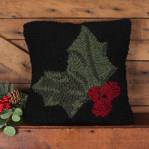 Holly Hooked Pillow featuring green holly leaves and bright red berries on a black hooked wool background.