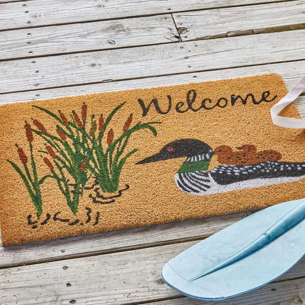 Our Rainy Lake Doormat will liven up your entryway and add warm welcome to your home.  Features a mother Mallard duck and ducklings on the water near cattails and the word Welcome.