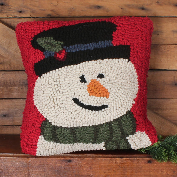 Flurry the Snowman hooked pillow featuring a smiling snowman with a black top hat and green scarf on a festive red background.