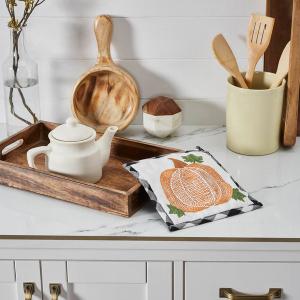 The Annie Black Check Pumpkin Trivet includes one trivet measuring 8x8 inches. The heat-resistant kitchen pad features buffalo check fabric with a thick layer of thermal cotton batting to protect from hot pots and pans. A whimsical pumpkin design is featured on the front with a convenient hanging loop