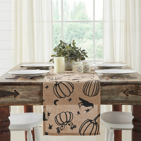 The Raven Harvest Burlap Jute Runner measures 12 by 48 inches and features a woven burlap base in natural tan. The textured Thanksgiving table runner features a whimsical pattern with stenciled black pumpkins, crows, stars and crescent moons.