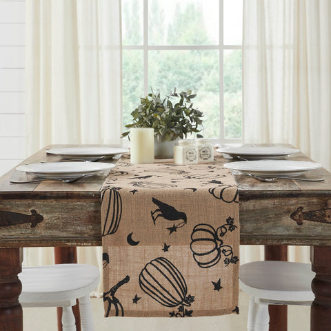 The Raven Harvest Burlap Jute Runner measures 12 by 60 inches and features a woven burlap base in natural tan. The textured Thanksgiving table runner features a whimsical pattern with stenciled black pumpkins, crows, stars and crescent moons. 