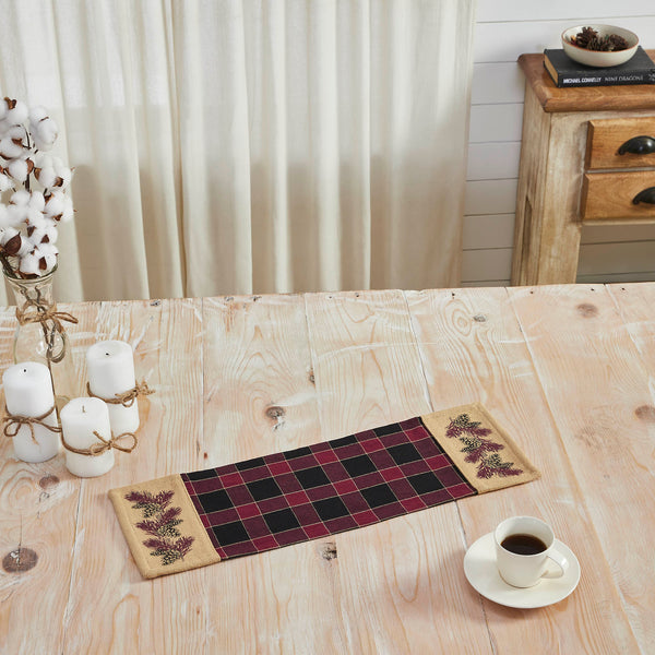  The Connell Pinecone Runner measures 8 by 24 inches and features a woven base in 100 percent cotton. The dark fall table runner features a burgundy and black plaid base flanked by tan blocks featuring a primitive pinecone and pine needle design. 