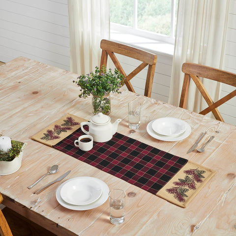 Give your tabletop decor a seasonal upgrade with traditional plaid in deep tones with pinecone accents. The Connell Pinecone Runner measures 12 by 36 inches and features a woven base in 100 percent cotton. The dark fall table runner features a burgundy and black plaid base flanked by tan blocks featuring a primitive pinecone and pine needle design. 