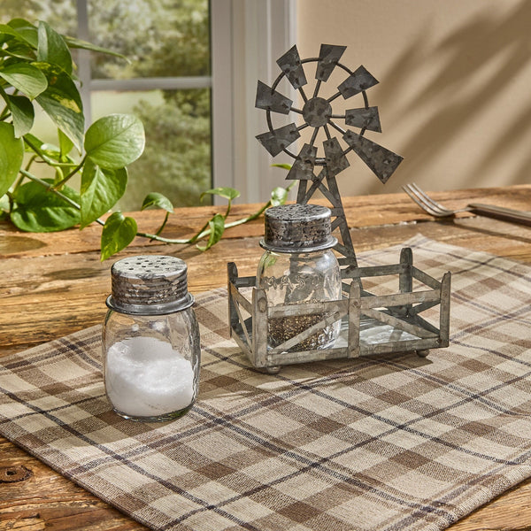 Rustic windmill salt and pepper set with glass shakers on a plaid farmhouse table runner