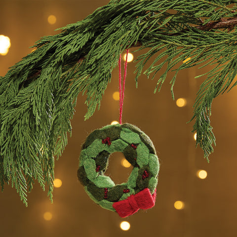 Wreath Felt Ornament is a felt ornament braided to depict a Christmas Wreath. It is accented with a red fabric bow and small read bead. Item is slightly filled for a weighted feel. Includes a string for hanging on the Christmas tree.