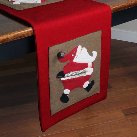 Ol' Saint Nick Table Runner featuring appliquéd Santa Claus designs with dimensional bell accents on a red background, perfect for primitive farmhouse Christmas decorating.