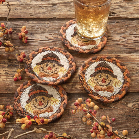 Set of 4 round scarecrow printed coasters in warm fall colors displayed on rustic wood table