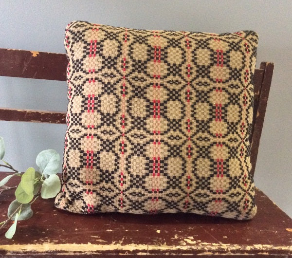 Patriot Knot 16×16 pillow in black, cranberry and tan on a rustic bench—primitive farmhouse coverlet pattern.