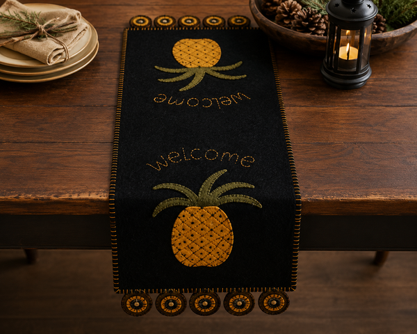 Pineapple Welcome Table Runner featuring traditional mustard-gold pineapples and welcome lettering on a black wool felt background.