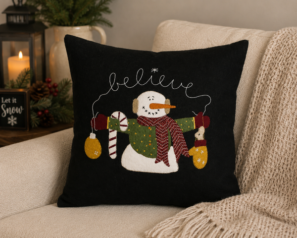 Spread a little holiday magic with the Snowman Believe Pillow. Set against a classic black background, a cheerful snowman—bundled in a patterned scarf and wooly mittens—holds festive trims while the word “believe” is stitched in a sweet, swirling script across the top. Crafted from soft wool felt with appliqué and embroidery, this accent delivers that cozy, handcrafted look that pairs perfectly with farmhouse and primitive Christmas décor.