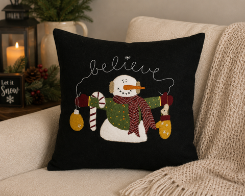 Spread a little holiday magic with the Snowman Believe Pillow. Set against a classic black background, a cheerful snowman—bundled in a patterned scarf and wooly mittens—holds festive trims while the word “believe” is stitched in a sweet, swirling script across the top. Crafted from soft wool felt with appliqué and embroidery, this accent delivers that cozy, handcrafted look that pairs perfectly with farmhouse and primitive Christmas décor.