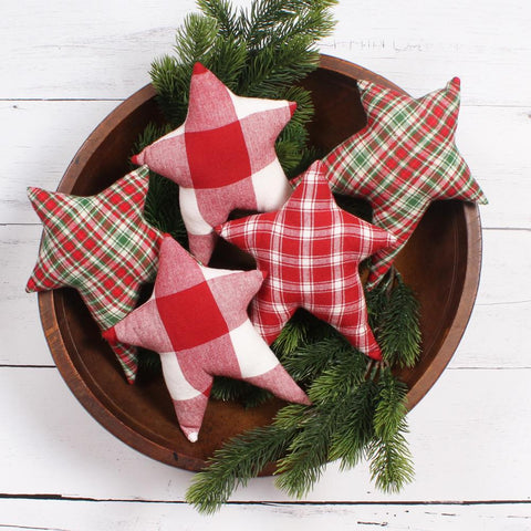 Primitive plaid fabric star bowl fillers displayed in a wooden dough bowl with evergreen branches.