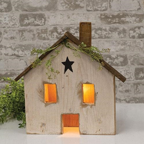 Light Up Rustic White Wood Farmhouse with distressed finish, black star accent, and glowing windows displayed as primitive farmhouse tabletop decor.