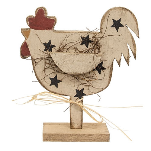Rustic Wood Stars Chicken on Base displayed on a farmhouse kitchen countertop beside a crock of wooden utensils. This primitive country chicken features distressed wood, black painted stars, raffia accents, and a freestanding wooden base, adding charming farmhouse style to kitchen shelves, countertops, and tabletops.