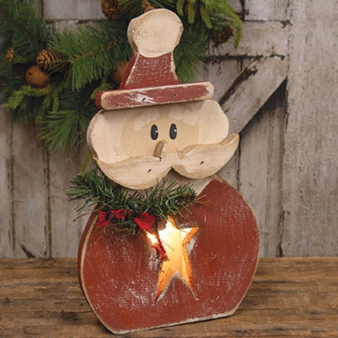 Primitive wooden Santa with glowing star belly, plaid scarf, greenery, and distressed rustic finish.