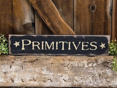 The Primitives Barnwood Sign is a decorative sign for the home, made of chunky distressed wood with a weathered finish in black paint. The sign reads “Primitives” in a traditional ivory font, complete with star designs.