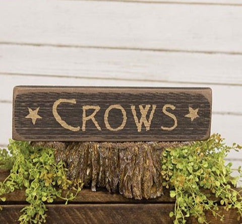 The Crows Barnwood Sign is a decorative sign made of raw natural wood with softly worn edges. The sign has a distressed black paint finish and reads “Crows” in rustic ivory lettering with star graphics, making it a fun and festive addition to the home for the Halloween season.