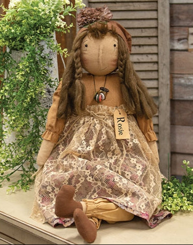 Vintage Rosie Blooms primitive fabric doll with braided hair, floral dress, and button necklace sitting against a rustic wooden backdrop.