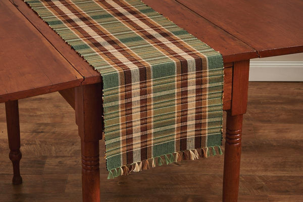 This gorgeous Wood River Table Runner features a simple yet elegant plaid pattern. The colors are beautiful deep greens and browns, warm neutrals, and some white for a wonderful accent. It also has fray detailing on both sides for added charm. Great for decoration, or even for a hot home cooked meal just out of the oven.