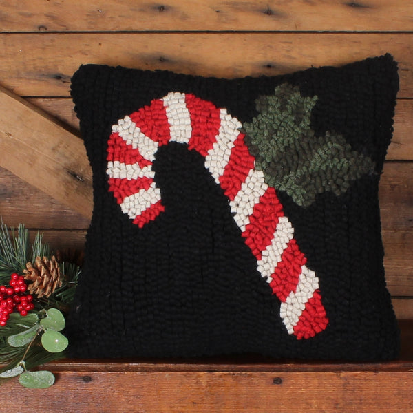Candy Cane Hooked Pillow featuring a red and cream striped candy cane with festive greenery on a black hooked wool background.