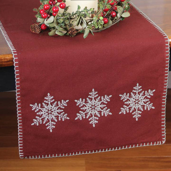 14x36 barn-red cotton table runner with embroidered snowflakes. Add classic farmhouse warmth to holiday tables, buffets, and consoles.
