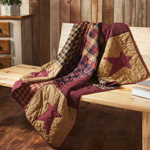 Connell Quilted Throw 50x60 in burgundy and tan patchwork design, draped on a country-style bed