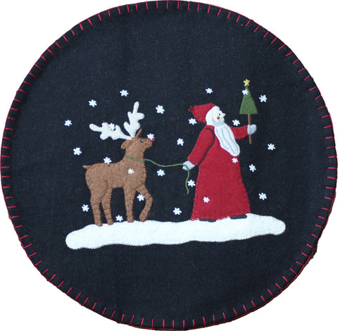Our Christmas Friends Candle Mat features detailled applique and embroidery of Father Christmas and his reindeer friend walking through a winter wonderland on a black ground with blanket stitch edge.