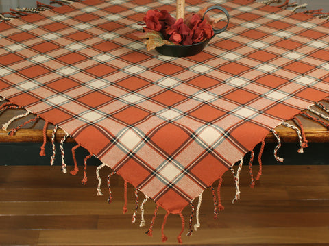 Harvest Moon Table Square 36" (set of 2) featues a plaid of pumpkin spice, black, and cream, finished with a hand braided fringe. 