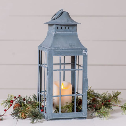 A compelling blend of historical beauty and modern cottage charm, this handsome square lantern is softened by an aged grey finish and a glass-free, openwork design. Ideal for filling with dried botanicals or live plants like moss or ivy, it's roomy and features pane-like designs on all four sides for threading branches or florals through. A ring at the top can be suspended from a cord or rope or hung on a wall hook for vertical decor.