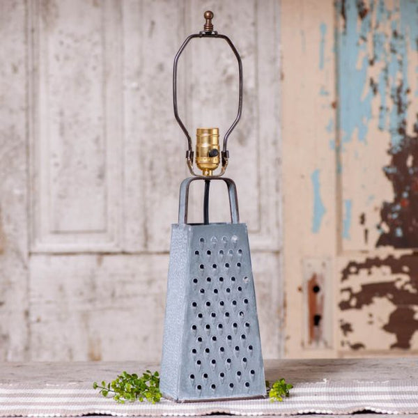 Made from galvanized tin, this lamp is shaped to look like an old-fashioned cheese grater. This lamp doesn't take up much space and can be placed a fair distance from the power outlet with its 7 feet cord. Takes up to a 150 watt standard base bulb. The rustic weathered zinc finish is reminiscent of an old water bucket that you saw as a child at your grandparent's farm. Does not include a shade. Metal Cheese Grater Lamp Base, Rustic Farmhouse Decor, Holds up to a 150-Watt Bulb